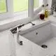 Küchenarmatur mit einem flexiblen Auslauf, montiert auf einer grauen Arbeitsplatte, neben einem Fenster. Ideal Standard Design, passend für Vorfenstermontage.